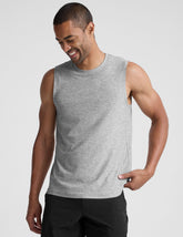 man wearing a gray sleeveless shirt against a plain background.